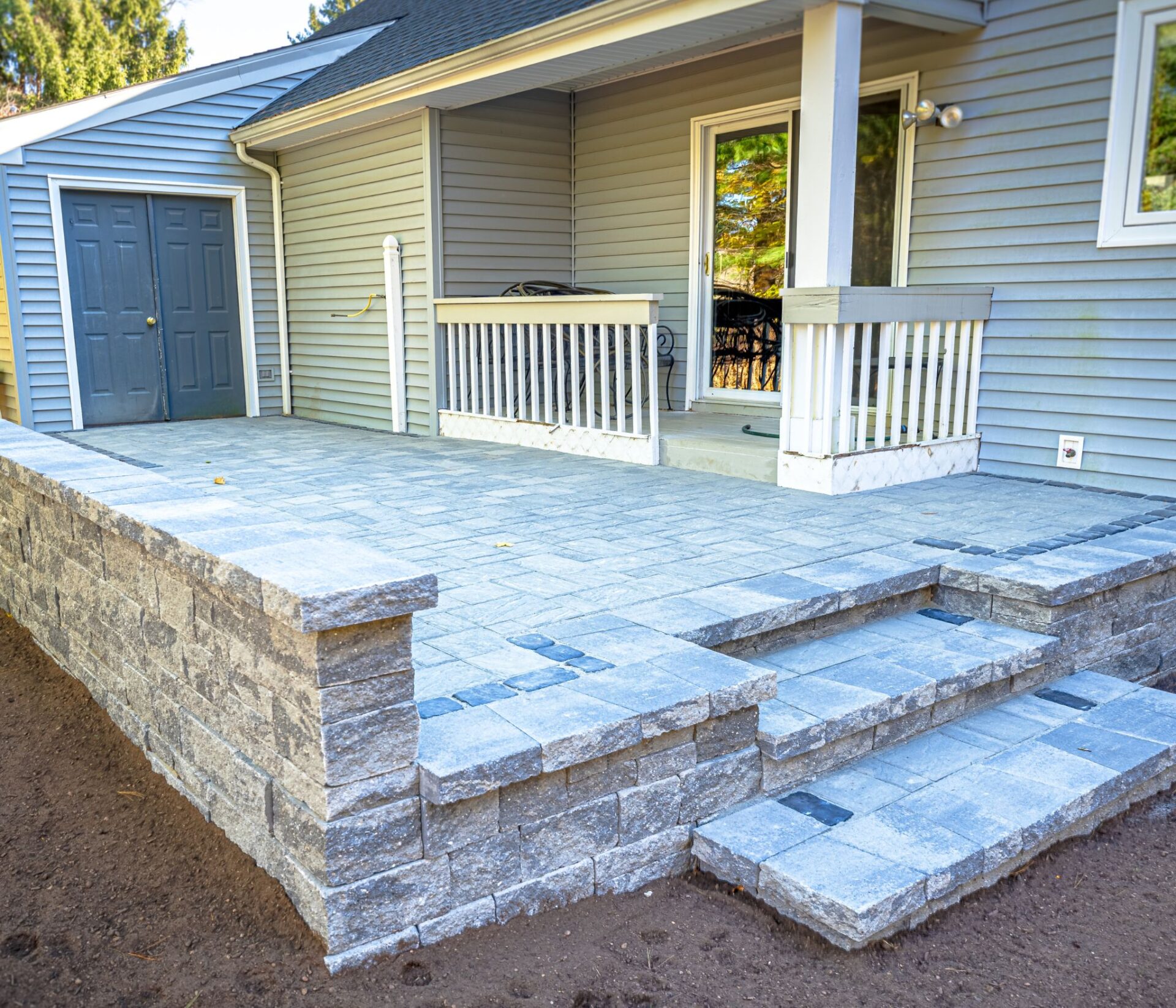 New custom paver patio installation with raised steps at a home in Southington CT by HQ Landscaping