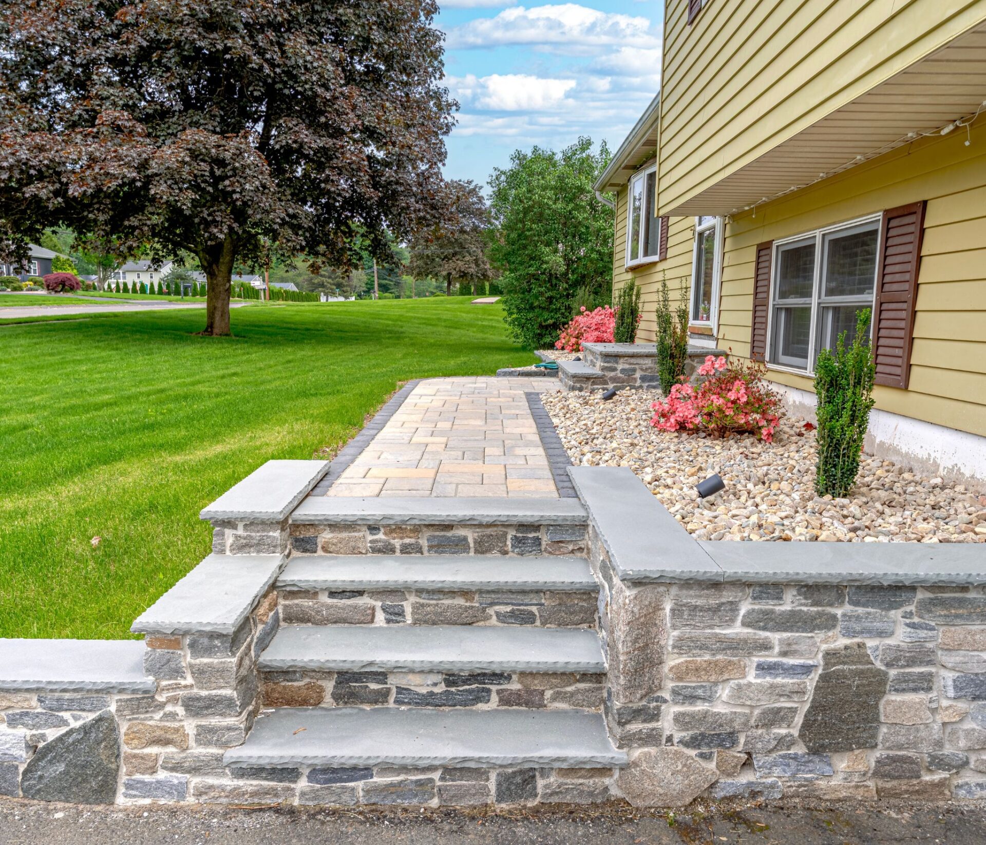 Stone front entry steps with paver walkway and foundation plantings at a home in Southington CT installed by HQ Landscaping
