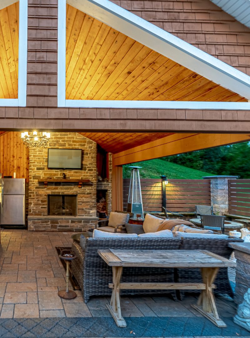 Berlin Fall Hardscape finish Covered outdoor living area with stone fireplace, paver patio, and seating built during a fall hardscaping project in Berlin, Connecticut.