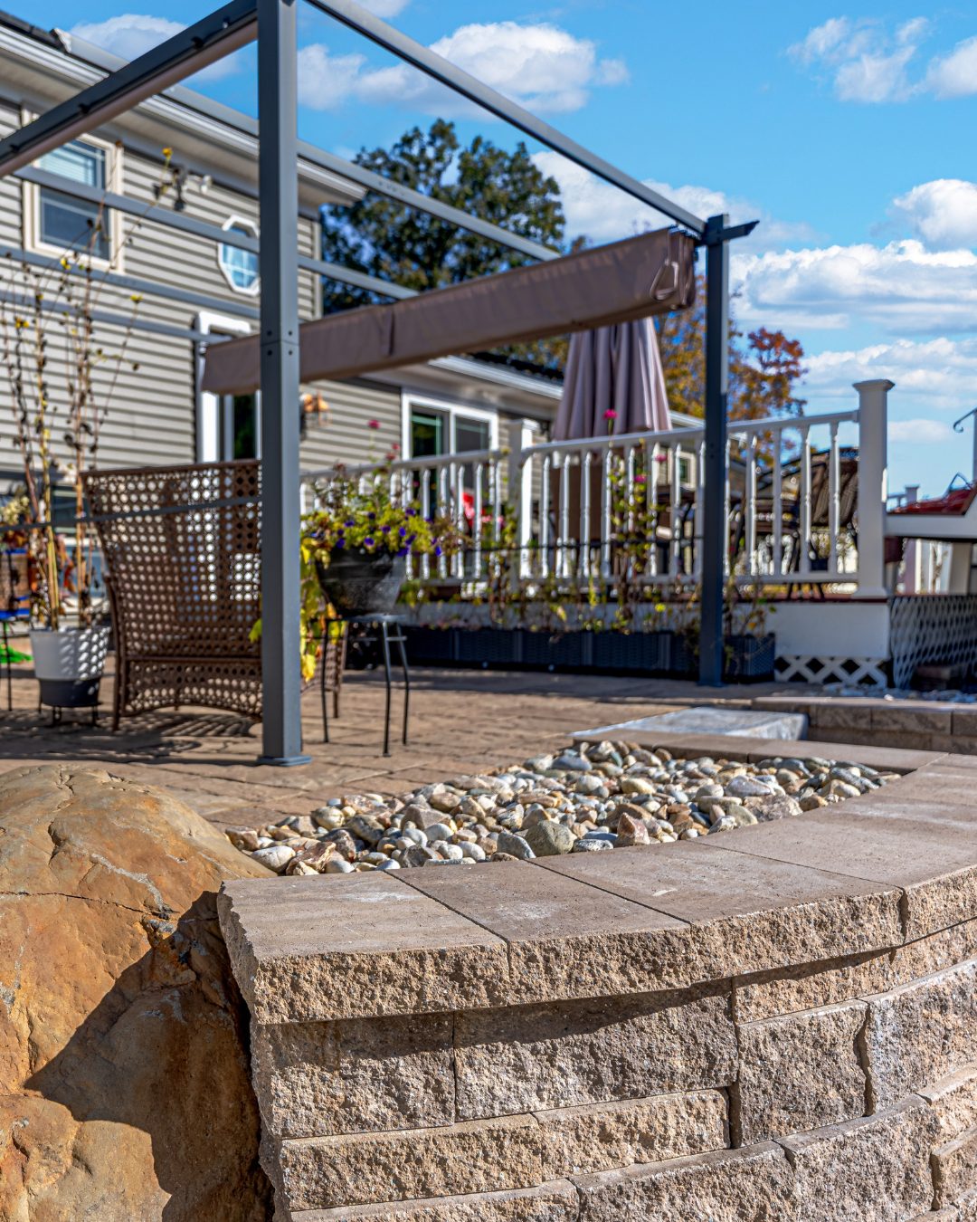 Patio retaining wall in Berlin ChatGPT said:</p>
<p>Patio retaining wall with stone cap and decorative river rock in a Berlin CT backyard. Modern outdoor seating area and pergola structure in the background.